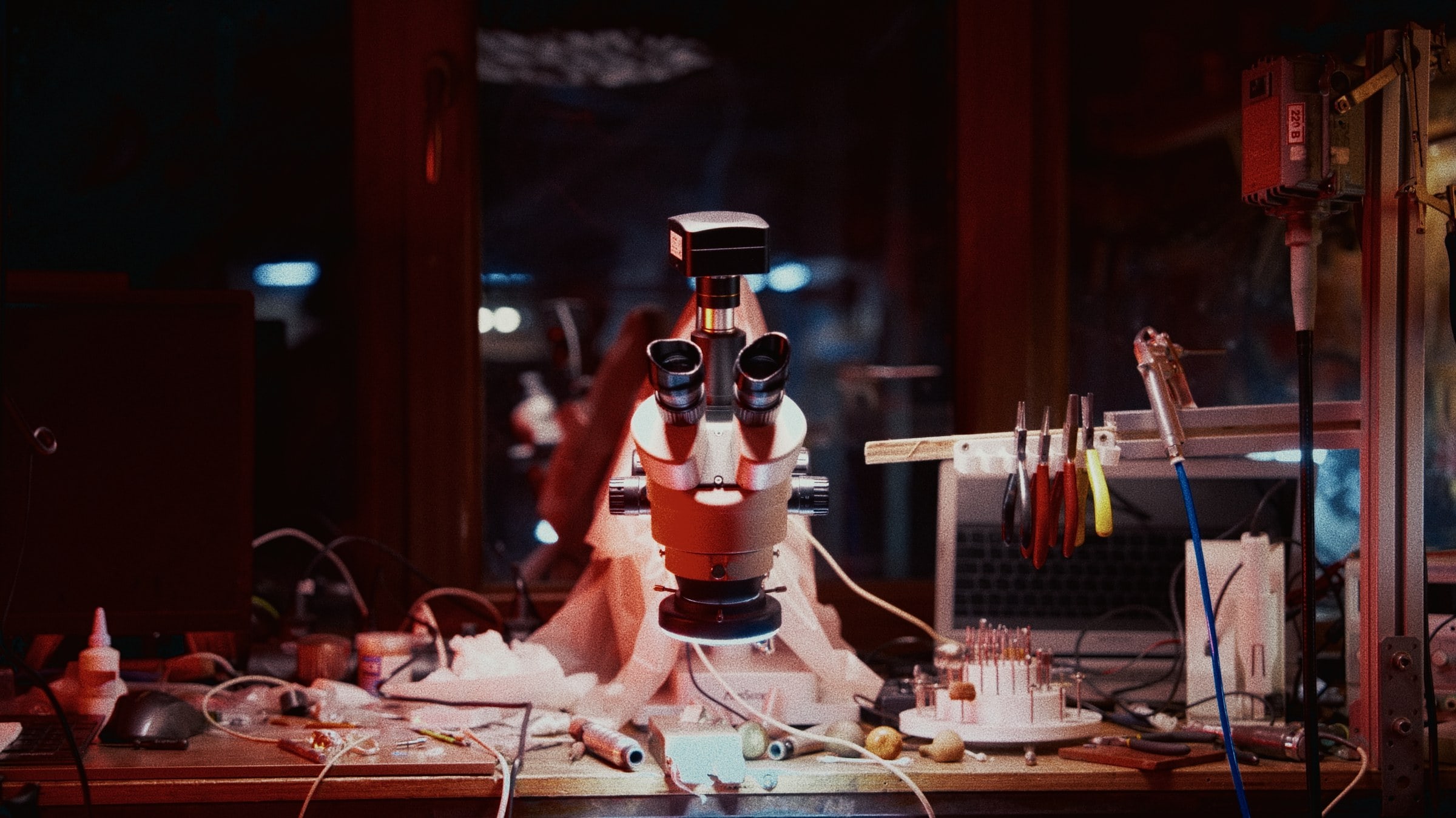 The workbench at night — microscope, tools, the workshop