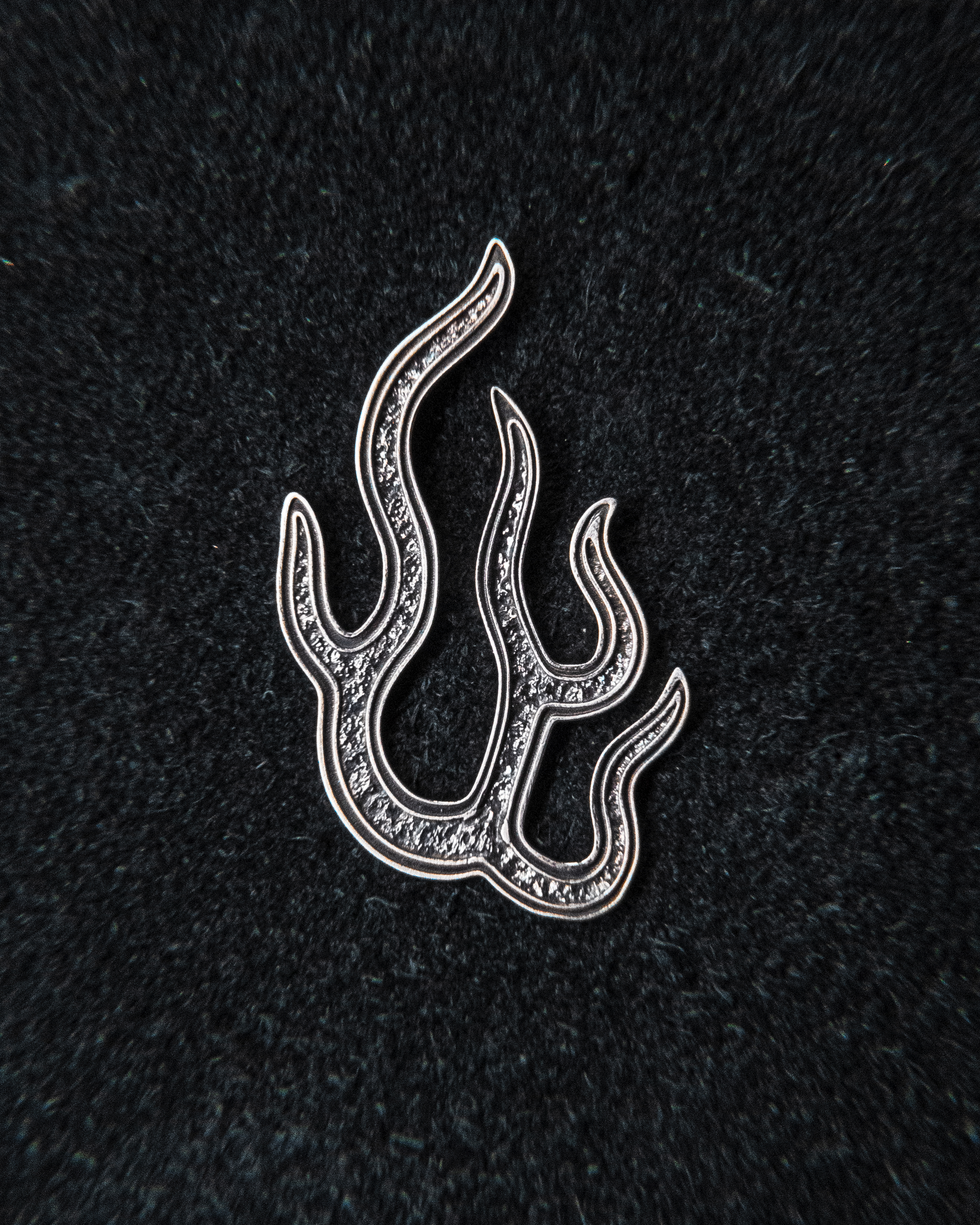 A silver flame brooch on dark cloth